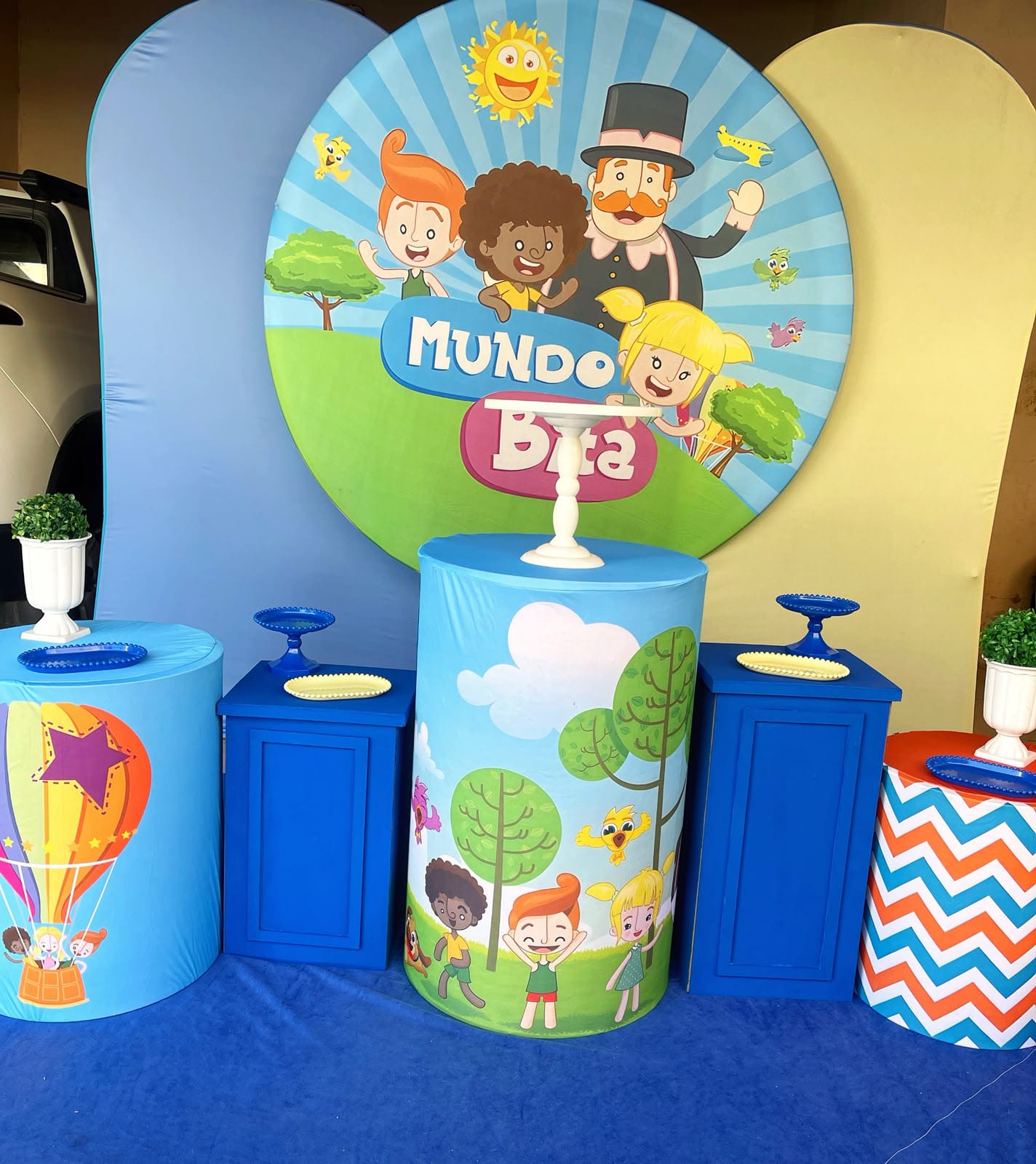 Decoração de festa infantil com painel do Mundo Bita e cilindros azuis coloridos